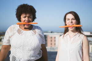 Two women chomp carrots